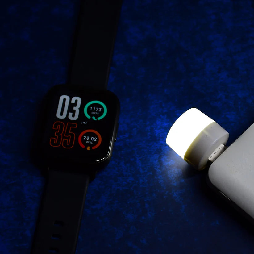 Smartwatch with fitness tracker display and portable USB LED light on blue surface
