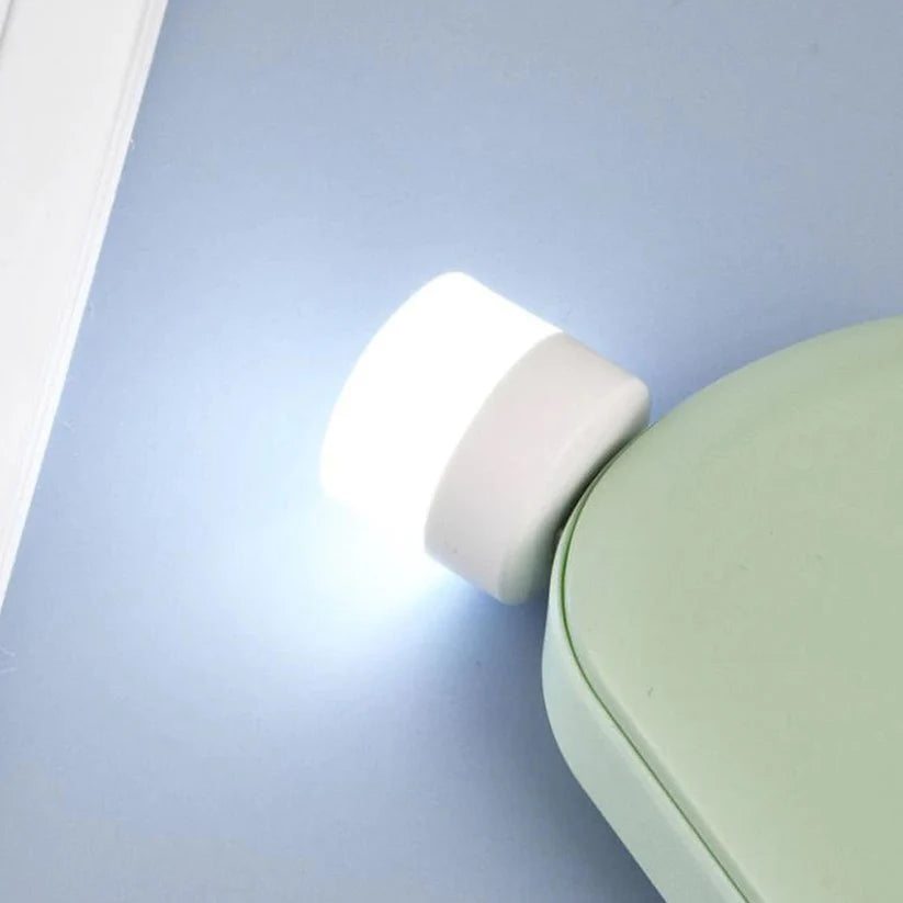 Compact LED night light plugged into a wall, emitting a soft white glow.